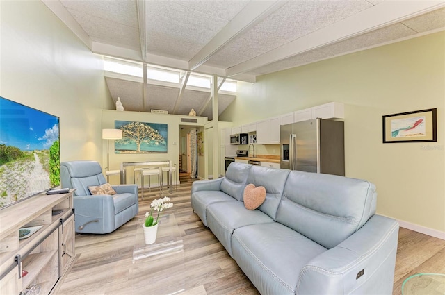 living room featuring beamed ceiling, high vaulted ceiling, sink, and light wood-type flooring