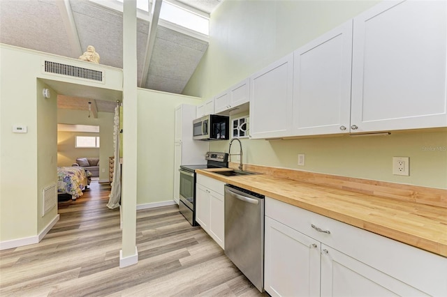 kitchen featuring white cabinetry, appliances with stainless steel finishes, sink, and butcher block countertops