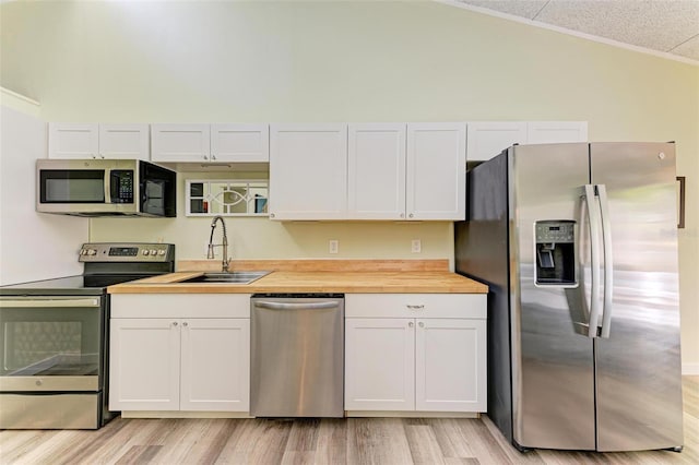 kitchen featuring butcher block counters, sink, stainless steel appliances, and white cabinets