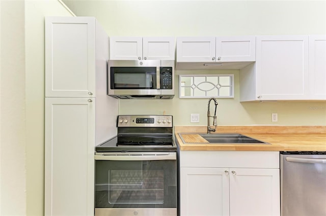 kitchen with white cabinetry, sink, stainless steel appliances, and butcher block counters