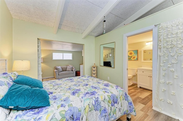 bedroom featuring connected bathroom, vaulted ceiling with beams, and light hardwood / wood-style flooring