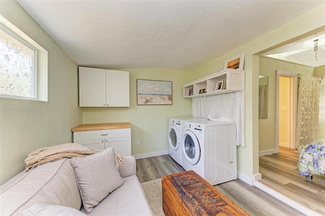 washroom featuring cabinets, separate washer and dryer, and light hardwood / wood-style flooring