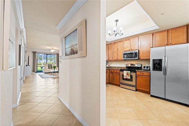 kitchen featuring light tile patterned flooring, decorative light fixtures, a raised ceiling, ornamental molding, and stainless steel appliances