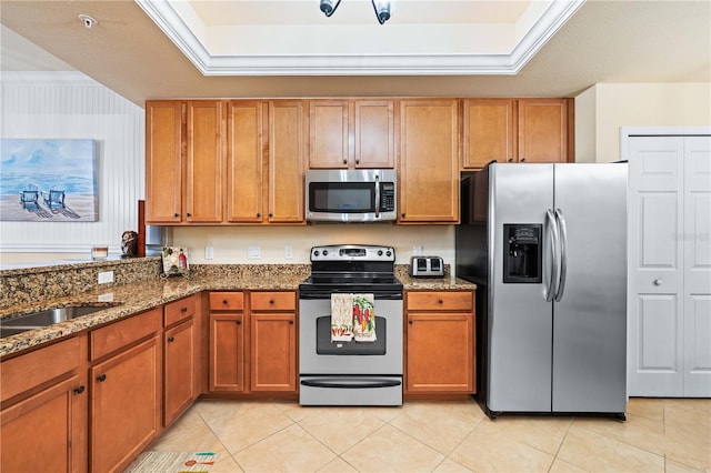 kitchen with light tile patterned floors, a tray ceiling, stainless steel appliances, and dark stone counters