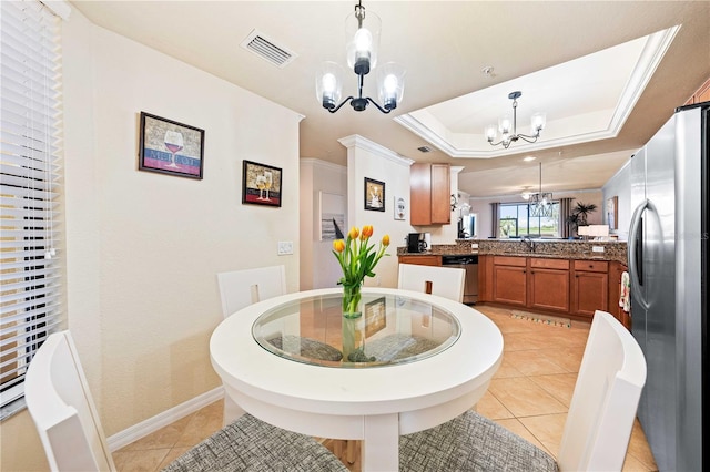 kitchen featuring appliances with stainless steel finishes, decorative light fixtures, kitchen peninsula, a raised ceiling, and an inviting chandelier