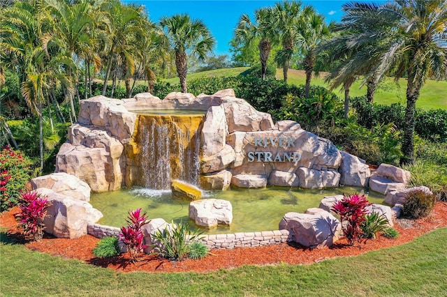 community sign featuring a yard and a garden pond