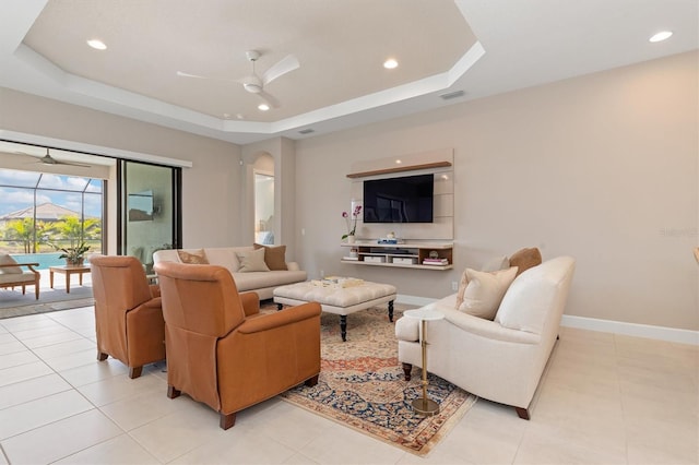 tiled living room featuring a raised ceiling and ceiling fan