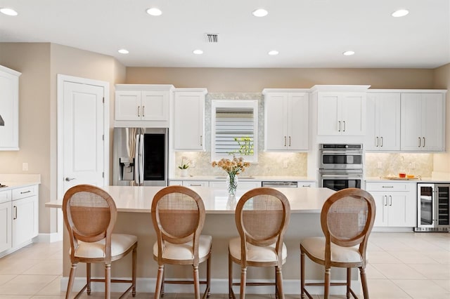 kitchen featuring wine cooler, white cabinetry, stainless steel appliances, and a kitchen island