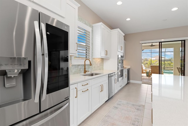 kitchen featuring stainless steel appliances, sink, white cabinetry, tasteful backsplash, and a healthy amount of sunlight