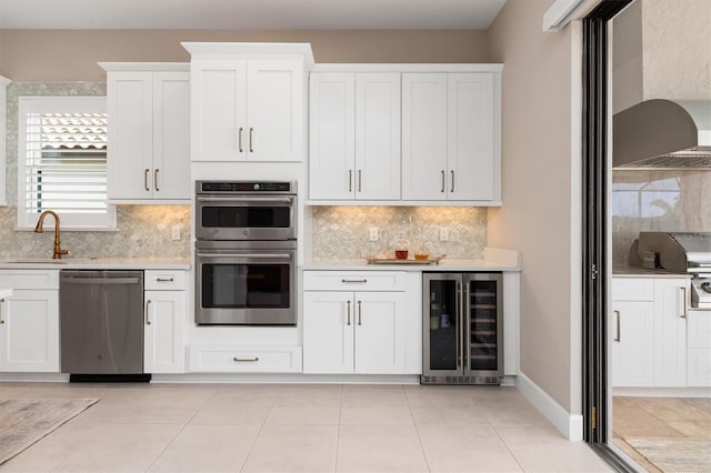 kitchen featuring stainless steel appliances, white cabinetry, sink, and wine cooler