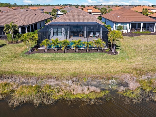 back of house with a lanai, a lawn, and a water view