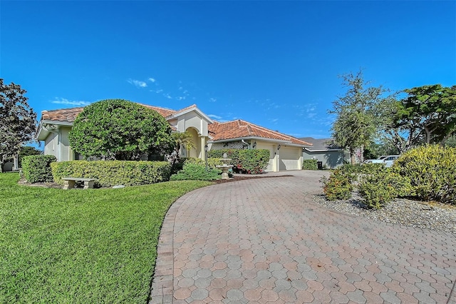 view of front of home featuring decorative driveway, stucco siding, an attached garage, a front yard, and a tiled roof