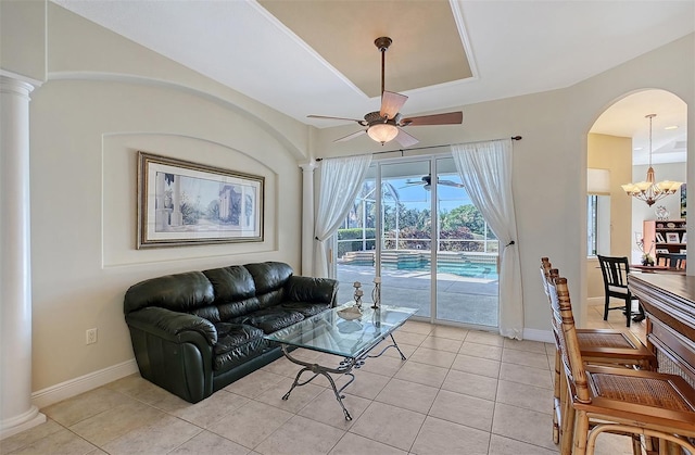 living room with ceiling fan with notable chandelier, decorative columns, and light tile patterned flooring