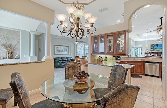 tiled dining area featuring sink, ceiling fan with notable chandelier, and ornate columns