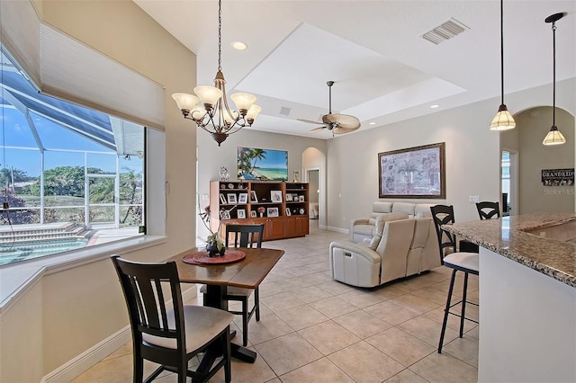 dining area with baseboards, visible vents, arched walkways, a tray ceiling, and light tile patterned flooring