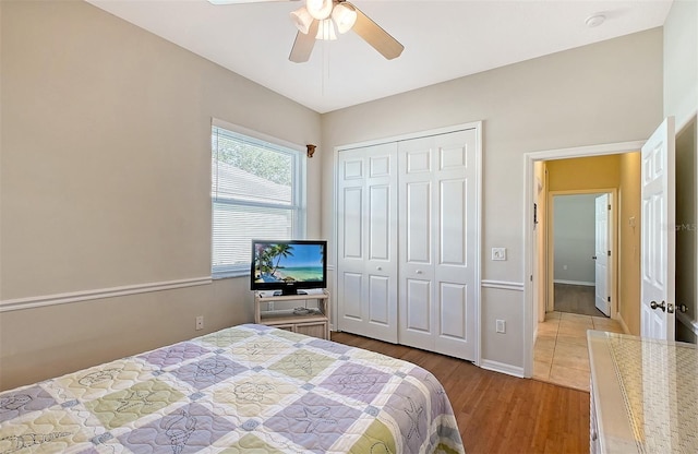 bedroom featuring a ceiling fan, a closet, baseboards, and wood finished floors