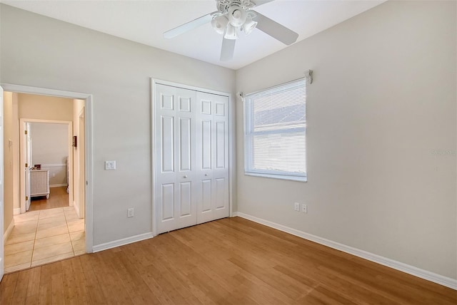 unfurnished bedroom with a ceiling fan, light wood-type flooring, a closet, and baseboards