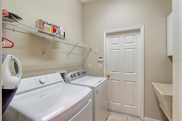 clothes washing area with laundry area, washing machine and dryer, and light tile patterned floors