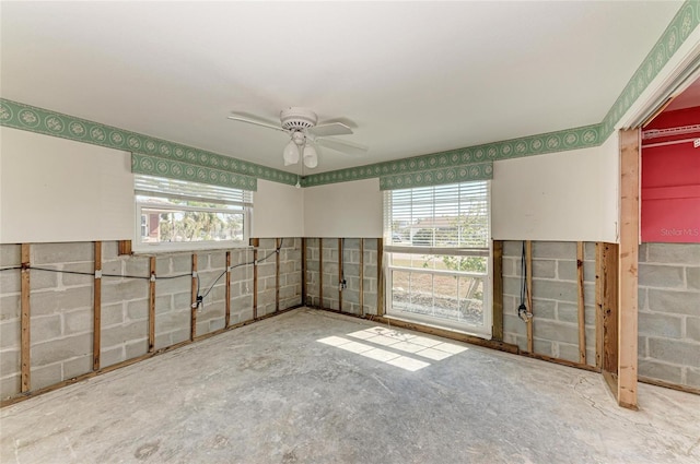 empty room with plenty of natural light, ceiling fan, and concrete floors