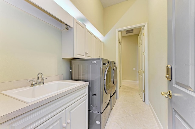 clothes washing area with sink, light tile patterned floors, washer and clothes dryer, and cabinets