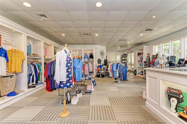 exercise room with a paneled ceiling and light carpet