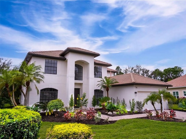 mediterranean / spanish house featuring a garage and a front yard