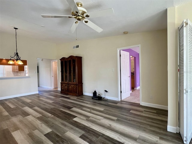 unfurnished living room featuring dark hardwood / wood-style floors and ceiling fan with notable chandelier