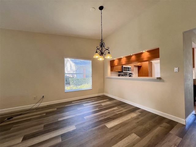 unfurnished dining area with dark hardwood / wood-style floors, a notable chandelier, and high vaulted ceiling