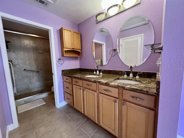 bathroom featuring vanity, tiled shower, toilet, tile patterned floors, and a textured ceiling