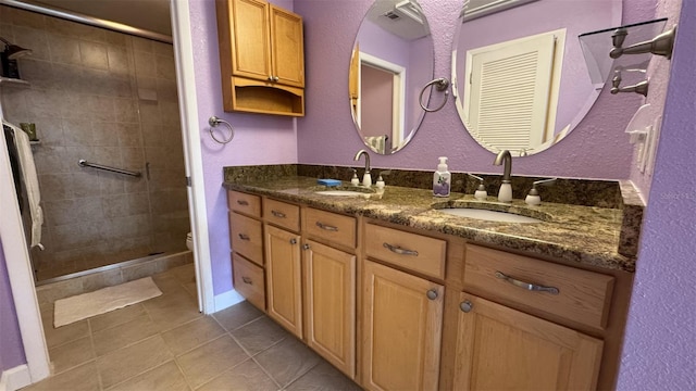 bathroom with vanity, tile patterned floors, toilet, and a tile shower