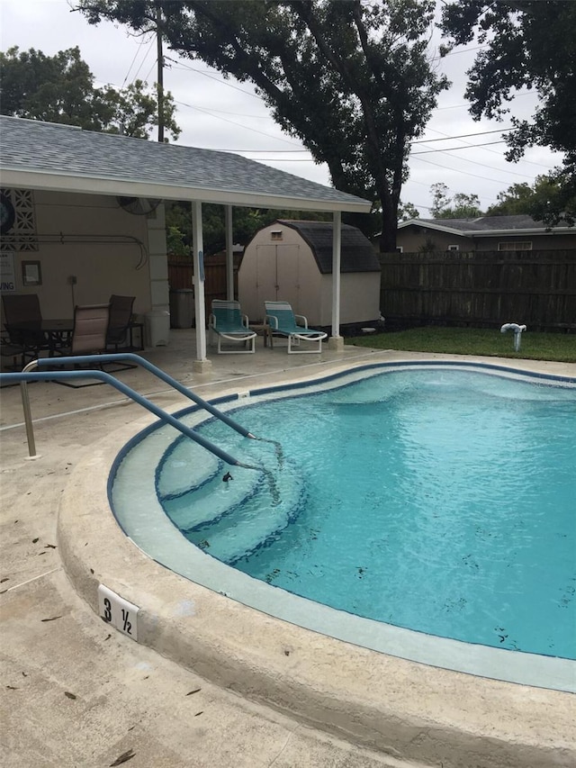 view of swimming pool featuring a storage unit and a patio area