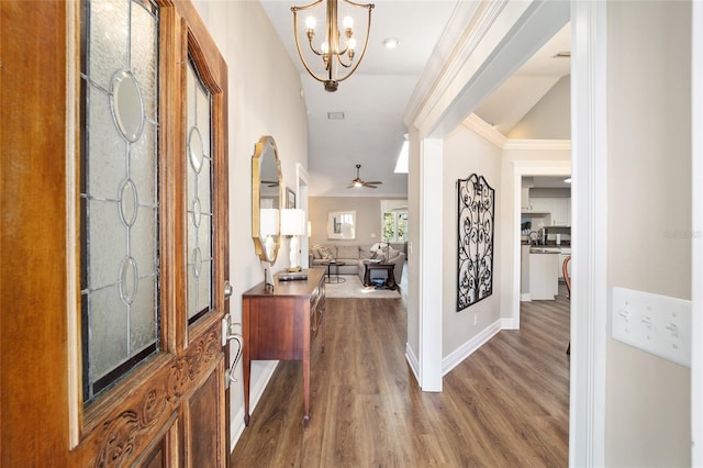 entryway with ceiling fan with notable chandelier, crown molding, baseboards, and wood finished floors