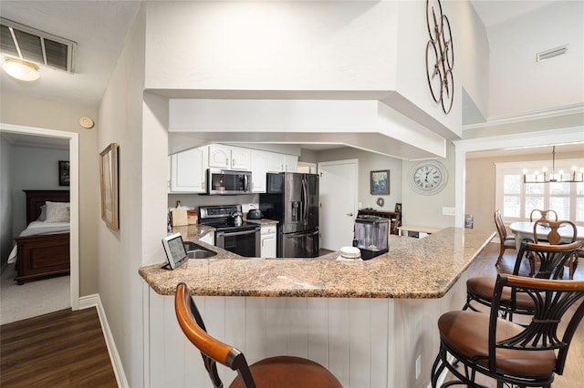 kitchen featuring stainless steel appliances, visible vents, white cabinetry, light stone countertops, and a peninsula