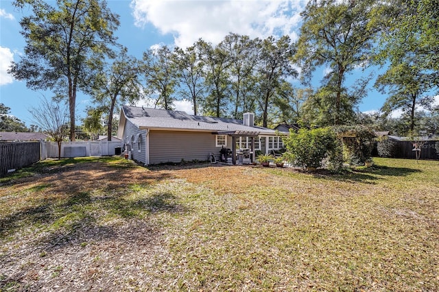 rear view of house featuring a fenced backyard, a yard, and a chimney