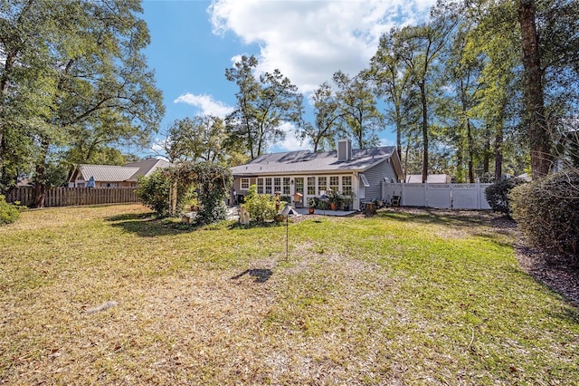 rear view of property featuring a fenced backyard, a chimney, and a yard