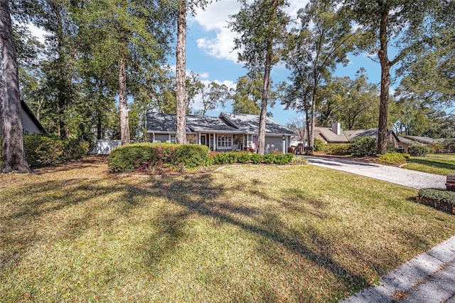 ranch-style home featuring driveway, a garage, and a front yard