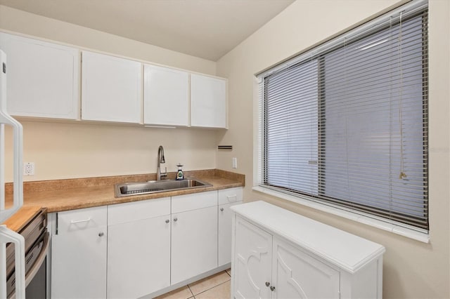 kitchen with white cabinetry, sink, and light tile patterned floors