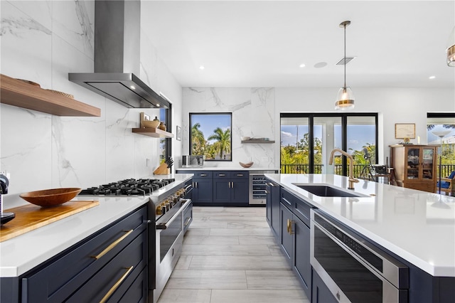 kitchen featuring blue cabinets, sink, beverage cooler, stainless steel appliances, and wall chimney exhaust hood