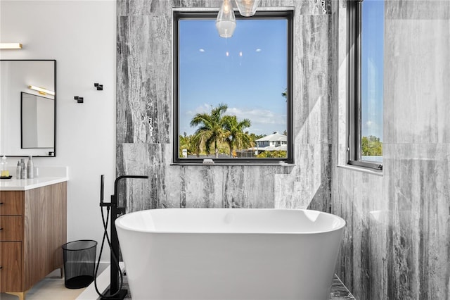 bathroom featuring vanity, a bathtub, and tile walls