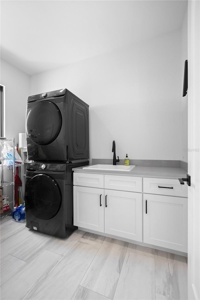 laundry area with stacked washer / dryer, sink, and cabinets