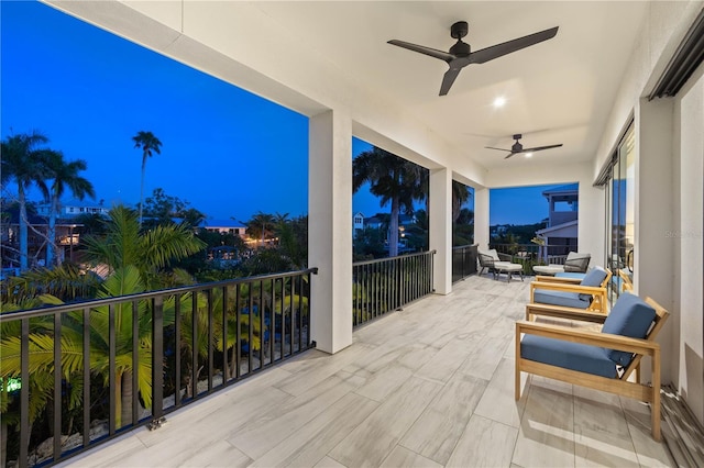 patio terrace at dusk featuring ceiling fan and a balcony