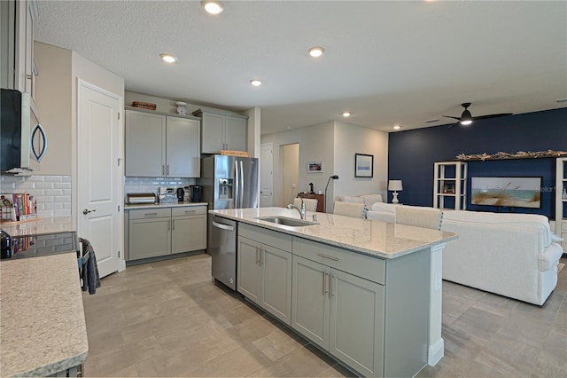 kitchen with gray cabinets, appliances with stainless steel finishes, sink, and a center island with sink