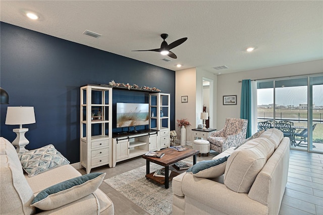 living room with a textured ceiling and ceiling fan