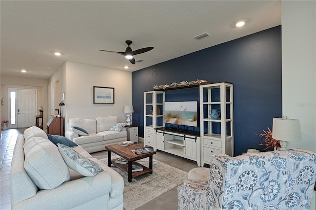 living room with ceiling fan, wood-type flooring, and a textured ceiling