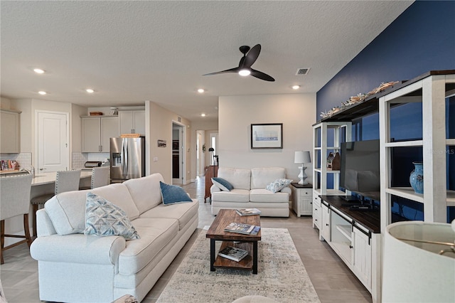 living room with a textured ceiling, ceiling fan, and light hardwood / wood-style floors