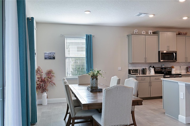 kitchen with appliances with stainless steel finishes, gray cabinets, a textured ceiling, and backsplash