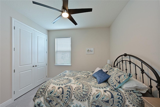 bedroom with ceiling fan, light colored carpet, a closet, and a textured ceiling