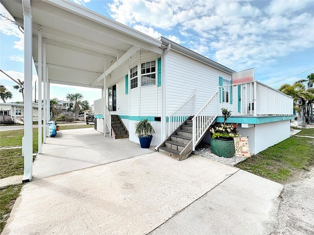 view of side of property with stairs, an attached carport, and driveway