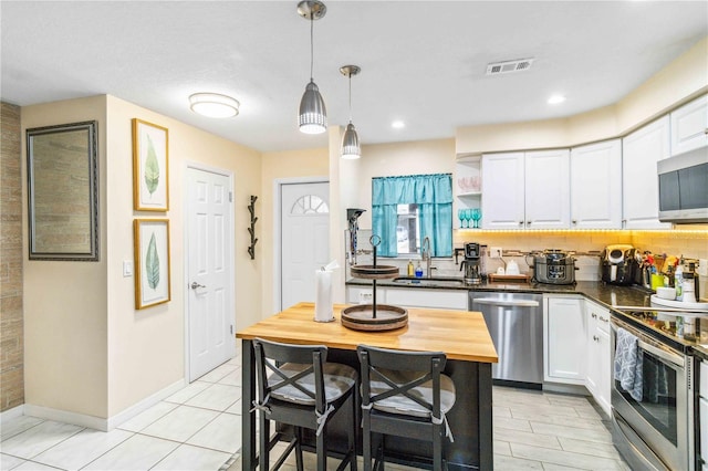 kitchen with white cabinetry, sink, decorative light fixtures, and stainless steel appliances