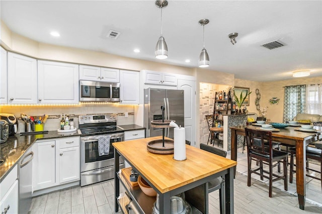 kitchen with white cabinetry, appliances with stainless steel finishes, decorative light fixtures, and decorative backsplash